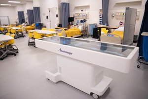Medical students learn in a simulation lab with an interactive table displaying skeletal anatomy.