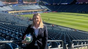 * Subject: A woman smiling, wearing a dark suit/blazer, holding a soccer ball.