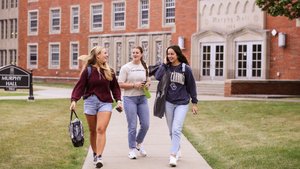 Three Young Women Walk Talk Sidewalk Front Brick